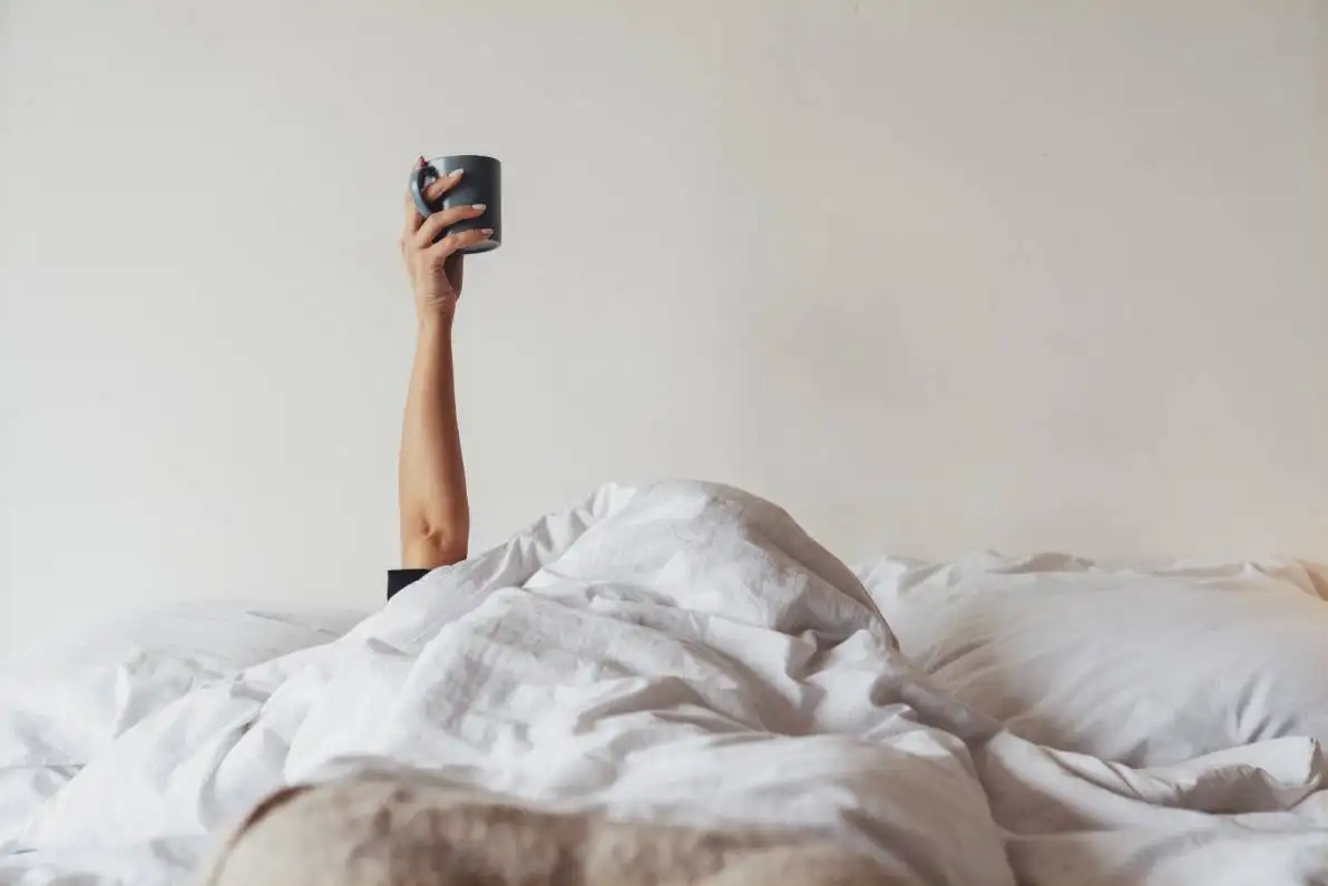 Femme dans son lit montrant sa tasse